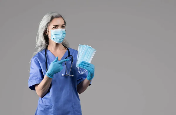 Fröhliche Krankenschwester Posiert Mit Schützenden Medizinischen Gesichtsmasken Zeigt Mit Dem — Stockfoto