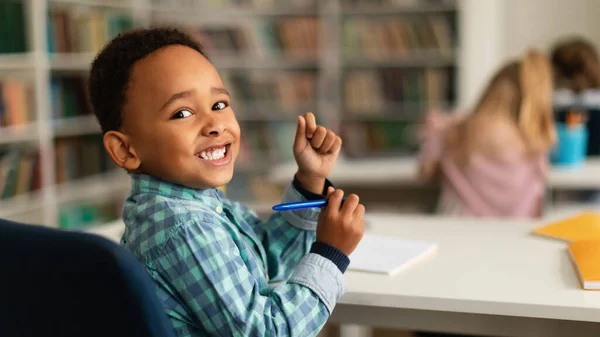Positive Black Primary Schoolboy Sitting Desk Classroom Looking Smiling Camera — Stock Photo, Image
