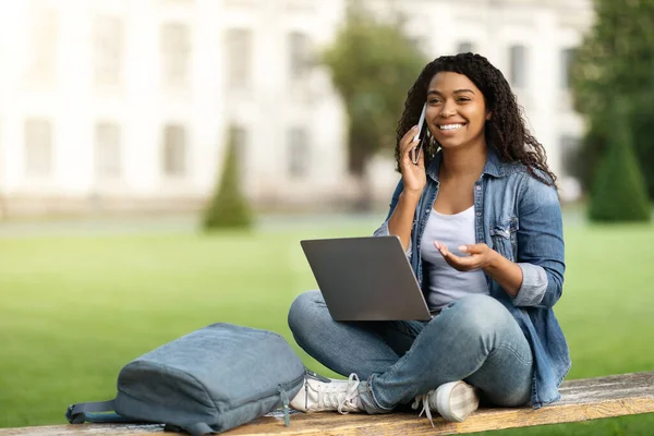 Cep Telefonuyla Konuşan Dışarıda Dizüstü Bilgisayar Kullanan Gülümseyen Siyahi Bir — Stok fotoğraf