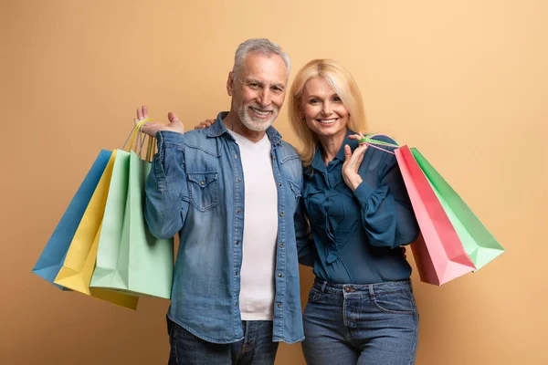 Gelukkig Gepensioneerd Stel Shopaholics Met Kleurrijke Boodschappentassen Poseren Beige Achtergrond — Stockfoto