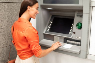 Banka Müşteri Kadını ATM 'yi para çekmek için kullanıyor, düğmelere basıyor, şifre giriyor, hesaptan parasını çekiyor ve dışarıda mali işlemler yapıyor,