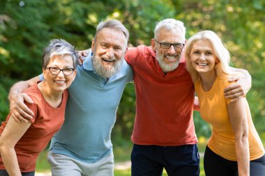 Eğitimden sonra dışarıda poz veren aktif kıdemli insanlar spor giyim kuşamında mutlu erkek ve kadınlar kameraya sarılıp bakıyorlar yaşlı arkadaşlar dışarıda antremandan keyif alıyorlar.