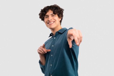 Sana bir teklifim var. Gülümseyen adam kamerayı işaret ederek Beyaz Stüdyo 'nun arka planında duruyor. Genç Milenyum Adamı Sırada Sen varsın, Reklam Sancağını Seçiyor