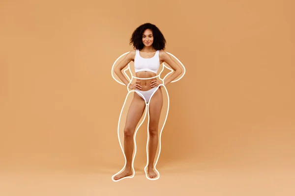 Body sculpting. Young sporty black woman in underwear with drawn outlines around figure stand isolated over beige background. Beautiful lady demonstrate result of weightloss, collage with copy space