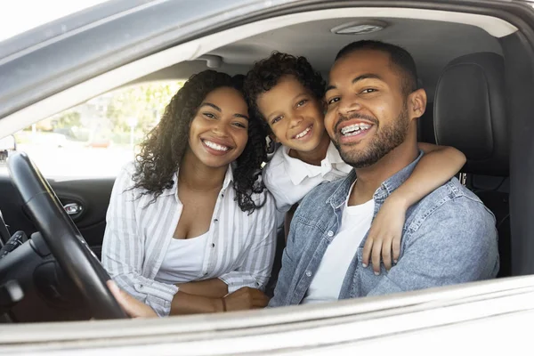 Happy african american family riding car traveling by automobile. Black parents and school aged son enjoying road trip together on weekend. Family leisure, affectionate, love, relationships