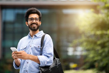 Gülümseyen yakışıklı, sakallı, genç bir doğu bilişim uzmanı ofise giderken akıllı telefondan kayıyor, fotokopi alanına bakıyor, güneş parlıyor. Mutlu bin yıllık Hintli adam internetten iş olanaklarını kontrol ediyor.