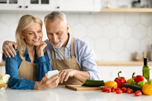 Lächelnde Ältere Ehepartner Mit Smartphone Der Küche Beim Gemeinsamen Kochen — Stockfoto