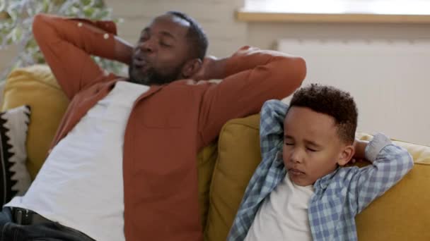 自宅で昼寝をする リラックスした黒人男性が自宅で瞑想し 息子にリラックスするように教え 目を閉じてソファーに座り ショットを追跡し ゆっくりとした動き 自由なスペース — ストック動画