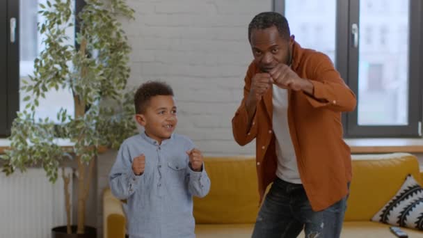 子供の頃からのスポーツ教育 スポーティなアフリカ系アメリカ人の父親は 息子のボクシングを教え パンチする方法を示し 自宅で一緒にトレーニングし ショットを追跡し スローモーション フリースペース — ストック動画