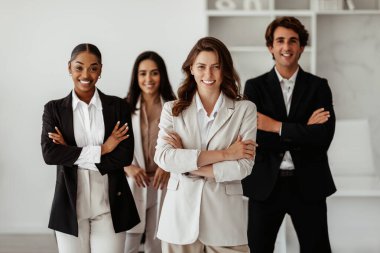 Avrupalı başarılı genç iş kadını hafif ofiste poz veren çeşitli iş adamlarının önünde kollarını kavuşturdu. Liderlik ve girişimcilik kavramı