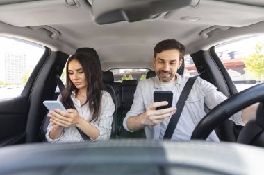 Millennial erkek ve kadın ön koltuklarda oturuyorlar, akıllı telefonlar kullanıyorlar. Otomobille bir yere giden çift cep telefonlarını kontrol ediyor, birbirleriyle konuşmuyorlar. Güvenli olmayan sürüş konsepti