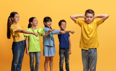 Öfkeli, acımasız, çok kültürlü gençler sınıf arkadaşlarına gülüp kulaklarını elleriyle kapatarak işaret ediyorlar. Okul çağındaki çocuklar çocuğa zorbalık yapıyor. Sosyal eşitsizlik sorunu. Okul çocukları yem atıyor.