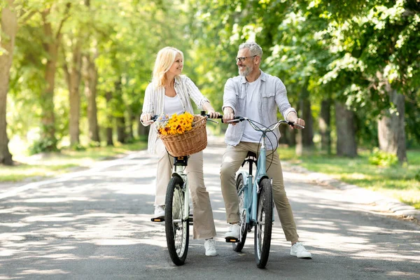 Older Age Activities. Happy Mature Couple Riding Bicycles Together In Park, Cheerful Senior Man And Woman Having Fun Outdoors, Enjoying Active Lifestyle On Retirement, Full Length With Copy Space