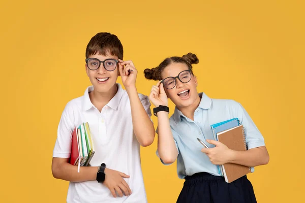 拿着书本戴眼镜笑着的欧洲少年学童在学校里玩得很开心 享受教育 在橙色的工作室背景下与世隔绝 友谊和童年生活方式 — 图库照片