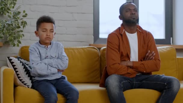 子供と両親のギャップ 怒ったアフリカ系アメリカ人の父親と彼の息子はソファーに座り お互いを見つめ合い 喧嘩の後に背を向ける 自由なスペース — ストック動画