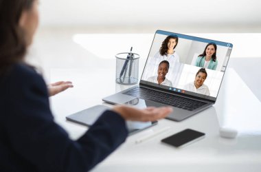 Olgun kadın CEO uluslararası takımla görüntülü görüşme yapıyor. Orta yaşlı yönetici kadın ofis işyerinde bilgisayar kullanıyor, el kol hareketi yapıyor, kırpılıyor. Haberleşme.