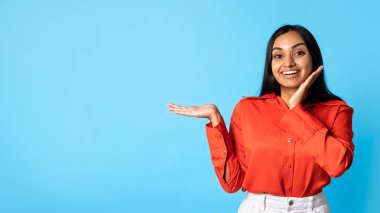 Buraya bak. Elle fotokopi çeken, görünmeyen nesneyi tutan, ürününüzün reklamını yapan ve Mavi Stüdyo 'nun arka planında durmayı teklif eden heyecanlı Hintli genç bayan,