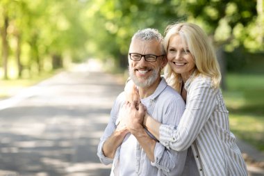 Mutlu olgun çiftler, yaz parkında dinlenirken, romantik son sınıf erkek ve kadın, kucaklaşıp, uzaklara bakıyorlar, eşleri dışarıda eğleniyorlar, boşluğu kopyalıyorlar.