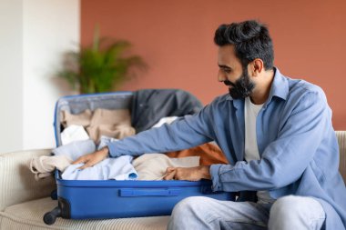 Hintli Gezgin Seyahat için hazırlanıyor bavullarını bavula dolduruyor, bavulunu valiziyle evde koltukta oturacak şekilde hazırlıyor. Turizm, İş Gezisi Hazırlığı