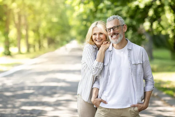 祝你退休愉快浪漫的老夫妇一起在阳光公园放松 快乐的成熟男人和女人拥抱并远眺 微笑的老年配偶享受户外时光 复制空间 — 图库照片