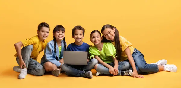 Симпатичные Дети Сидящие Полу Использующие Ноутбук Вместе Изолированы Желтом Фоне — стоковое фото