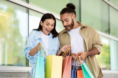 Genç Avrupalı kadın ve erkeğin çantalara bakması, alışveriş merkezlerinden alışveriş yapmaları beni şok etti. Müşteriler için alışveriş kolikleri, satış, indirim ve sürpriz, insan duyguları, yaşam tarzı