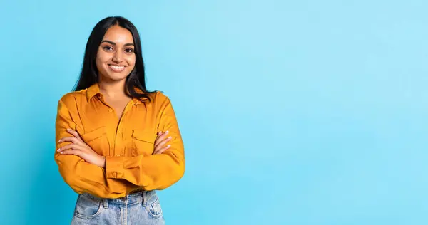 青い背景に立っている自信のある若いインドの女性の交差手の肖像画 カメラを見ているカジュアル笑顔の女性のスタジオショット パノラマ テキストのための空のスペース 広告バナー — ストック写真