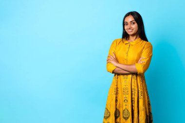 Geleneksel Sarı Elbiseli Güzel Bayan Harika Moda ve Güzellik Sunucusu Mavi Stüdyo Arkaplan 'ın yanında duruyor ve kameraya gülümsüyor.