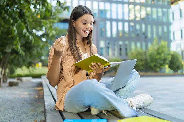 ハッピーな若い女性学生は 教師とのビデオレッスンを持っています 公園でベンチに座って ラップトップコンピュータを使用して メモを取る コピースペース オンライン教育 ウェビナー コース — ストック写真