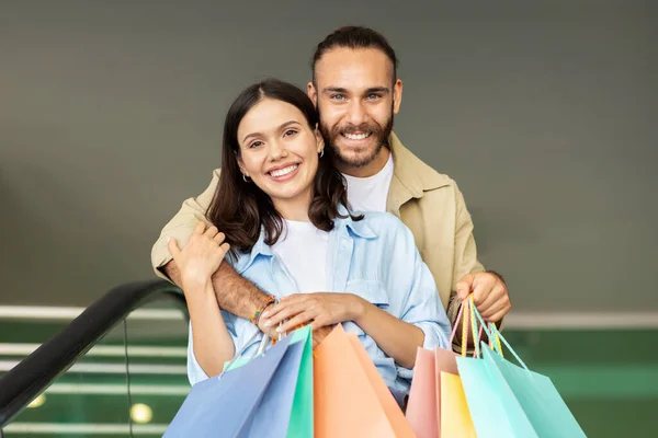 一个积极的欧洲小伙子 带着提包拥抱女人 享受购物 销售和闲暇时间 走进商场 城市的购物狂 生活方式 爱情和关系 广告和服务 — 图库照片