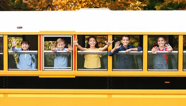 Groep Van Gelukkige Kinderen Zwaaien Handen Terwijl Gluuren Uit Schoolbus — Stockfoto