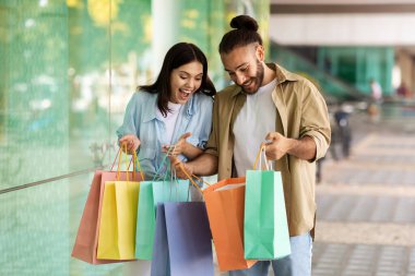 Gülümseyen Avrupalı genç alışverişkolikler alışveriş merkezlerinde alışveriş yapan torbalara bakarken şok oldular. Hediye, satış ve indirim, sürpriz, şehirde insanların duyguları ve yaşam tarzı