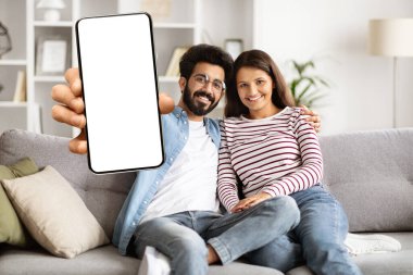 Evdeki kanepede oturan sevimli mutlu milenyum çifti, fotokopi alanı olan beyaz ekranlı telefon gösteriyorlar, online teklif için model alıyorlar, mobil uygulama reklamları yapıyorlar. İnternetten alışveriş, yemek siparişi.