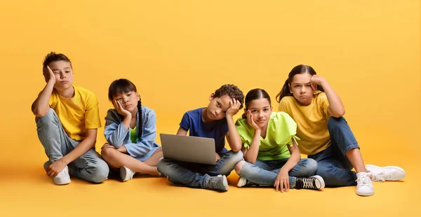 Znudzone Nieszczęśliwe Zróżnicowane Dzieci Wieku Szkolnym Siedzące Podłodze Laptopem Odizolowane — Zdjęcie stockowe