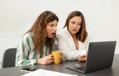 İki iş arkadaşı laptopta sorun yaşıyor, ofis masasında birlikte çalışırken bilgisayar ekranında şoka bakıyor. Kötü haber, İş Yeri İnternet Bağlantı Sayısı