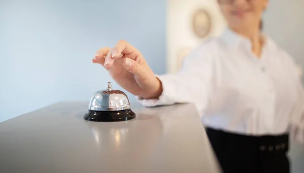 Hotel Service. Unrecognizable Businesswoman Pushing Call Bell At Reception Counter, Standing Indoors, Calling Receptionist For Check In, Cropped Shot, Selective Focus. Business Travel Accommodation
