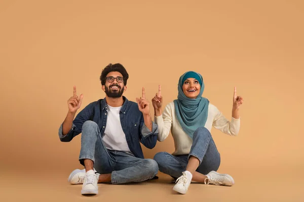 Happy Young Arab Couple Pointing Copy Space Boven Hun Hoofden — Stockfoto