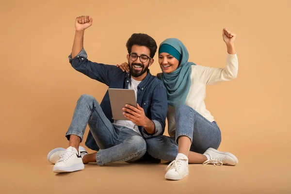 Šťastný Mladý Muslim Pár Pomocí Digitální Tabletu Slaví Úspěch Zatímco — Stock fotografie