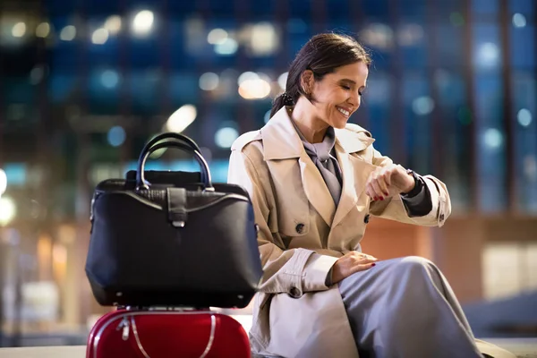 女商人坐在候机室等着飞机 快乐的中年妇女带着行李坐在机场候机室 看着手腕上的手表 检查时间 公务旅行 — 图库照片