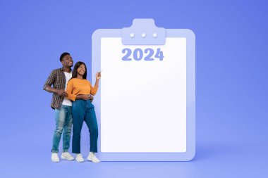 Gülümseyen Afrikalı genç bir Amerikalı erkek ve kadın fotokopi alanı ile büyük bir planın yanında sarılıyorlar, mavi stüdyo arka planında izole edilmiş. 2024 yıllık aile planlaması, motivasyon ve yaşam tarzı