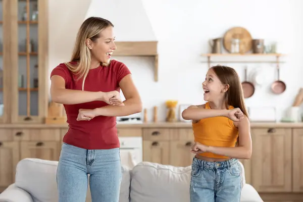积极迷人的金发千禧年女人妈妈和可爱的少女女儿在家里跳舞很开心 她们的胳膊也在动 互相望着笑着 享受在一起的时光 — 图库照片