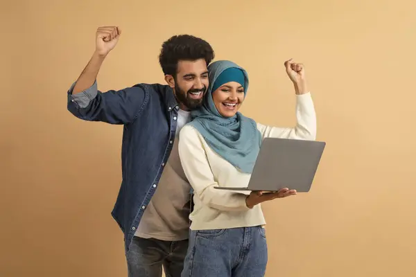 온라인 노트북을 성공을 즐거운 무슬림 남자와 히잡에서 컴퓨터 화면을 주먹을 — 스톡 사진
