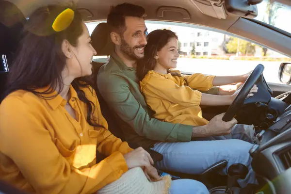 快乐的家庭驾驶汽车在一起 女孩学习驾驶坐在父亲的膝上 手握方向盘 父母和孩子有公路旅行的经历 — 图库照片