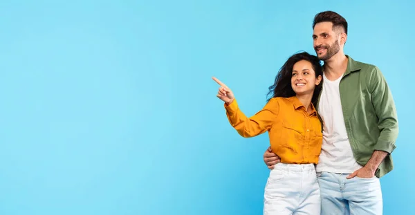 素晴らしい広告と提供 ハッピーヨーロッパのカップルが抱擁し 青い背景 パノラマで隔離された空のスペースを指す女性 オンライン販売とプロモーション — ストック写真