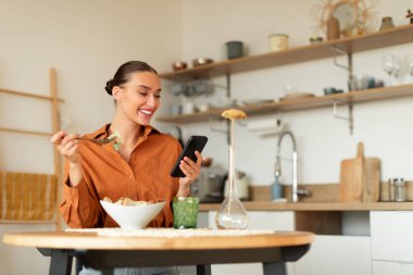 Lezzetli yemek yiyen, salata yiyen, cep telefonu kullanan, yemek yerken masada oturan, teslimat ve restoran servisini eleştiren, fotokopi çeken,