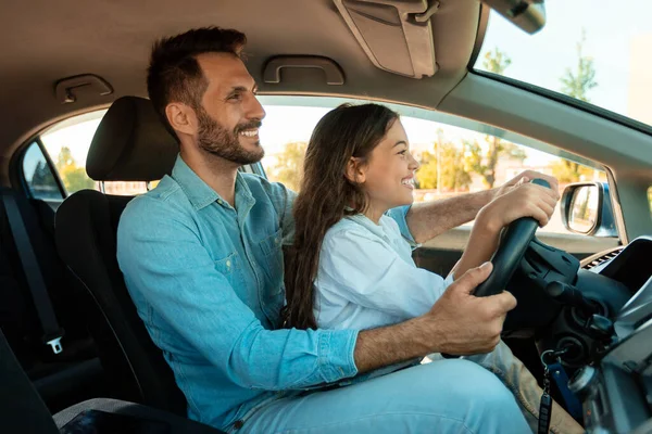快乐的年轻父亲和未成年女孩一起开车 孩子和爸爸坐在一起 手牵着方向盘 — 图库照片