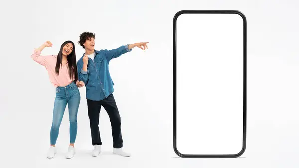 Young Couple Posing Large Cellphone Blank Touchscreen Having Fun Pointting — Stock fotografie