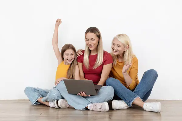 兴奋的爱着美丽的家庭三代女人妈妈 女儿和奶奶坐在空房间的地板上 一起使用笔记本电脑 上网购物 享受网上购物 — 图库照片