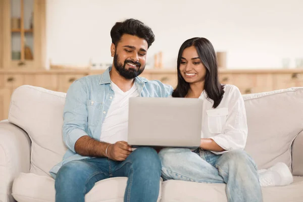 ハッピー若いインドの配偶者 ソファーでラップトップでリラックス コンピュータを使用してヒンドゥーのカップル リビングルームでのソファーで一緒に休む インターネットを閲覧したり オンラインショッピング — ストック写真