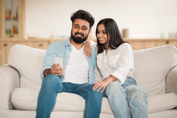 自宅でソファーに座ってリラックスした若いインドのカップル スマートフォンや笑顔 オンラインショッピング インターネットでサーフィン コピースペース — ストック写真